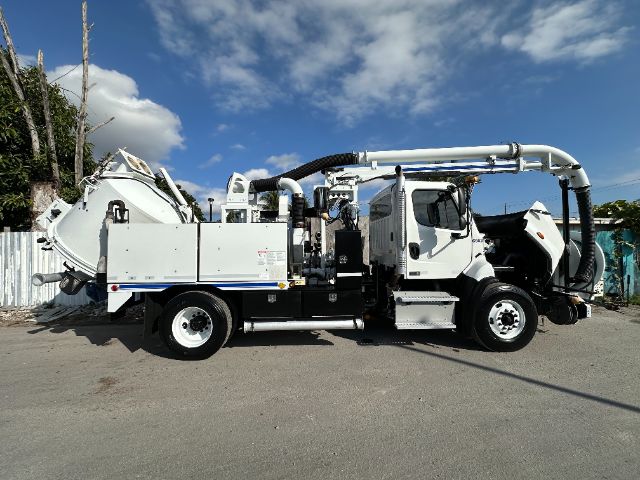 Vehicle side view of a 2016 Freightliner 108SD vacuum truck with mounted vacuum system and hoses.