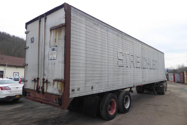 Trailer hitch in a used 1961 Brown 40BVAC2U trailer with dual rear doors, metal corrugated sides, and dual rear axles in a yard.
