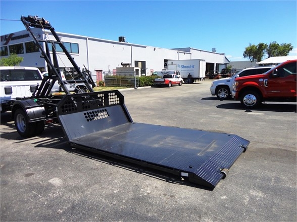 2024 Ram 5500 HD hooklift truck with a low-profile flatbed in a dealership lot.