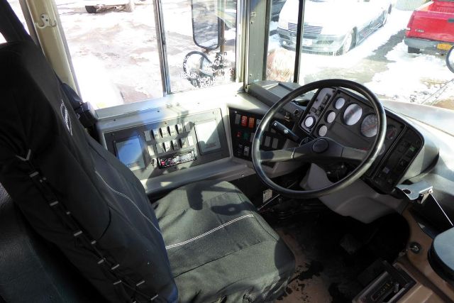Cab interior of a 2002 Freightliner FS65 bus showing steering wheel, dashboard with gauges, and driver seat.