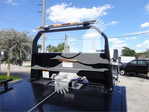 Isuzu NRR truck bed with headache rack and light bar, black metal rear view showing flatbed surface and wheel area.