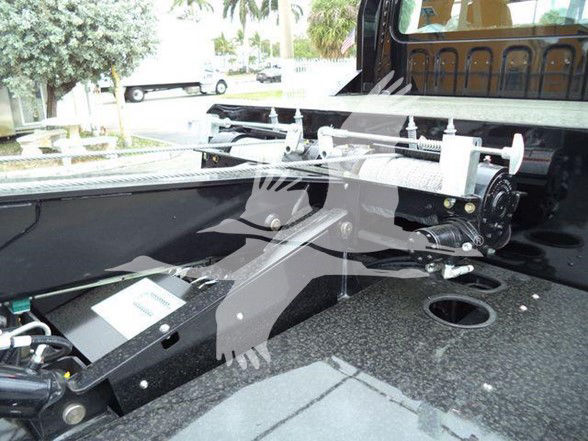 Freightliner M2 106 truck bed with hydraulic hoist and tie-down rails visible, mounting hardware, and operator cabin in background.