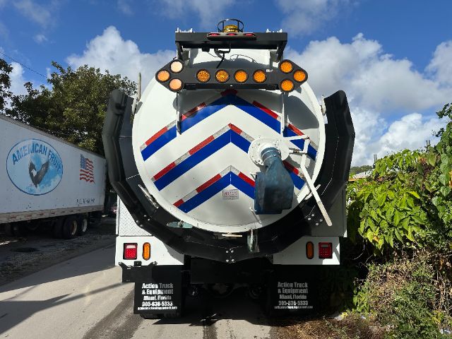 back of a 2014 Freightliner 114SD vacuum truck showing rear bumper, chevron-patterned tank, fold-down steps, lights, and mud flaps with equipment company contact information.