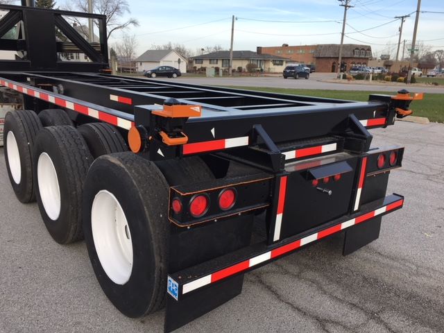 Trailer rear view showing a black Wabash tipper chassis with white wheels and red/white reflective tape.