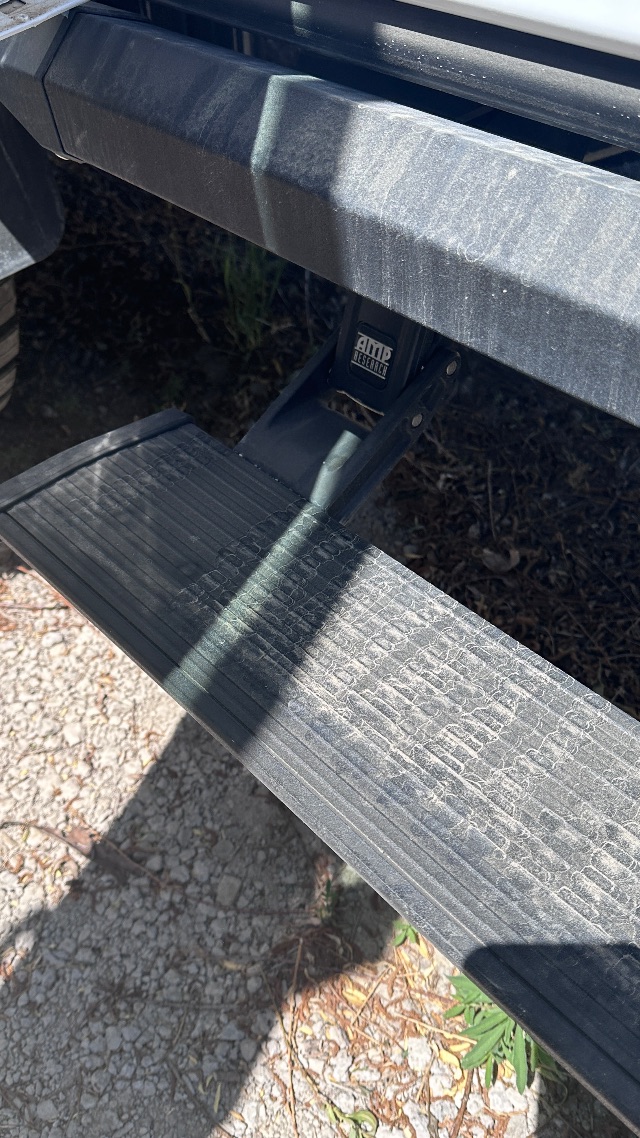 Ford F-550 cab and chassis step with AMP Research logo on step mount.