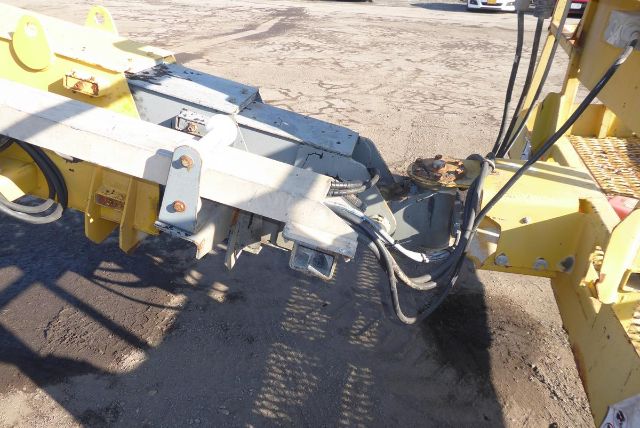 Grove T60 boom lift underside showing hydraulic hoses and metal linkages at joint, yellow paint, black hoses, and rust-free metal surfaces.