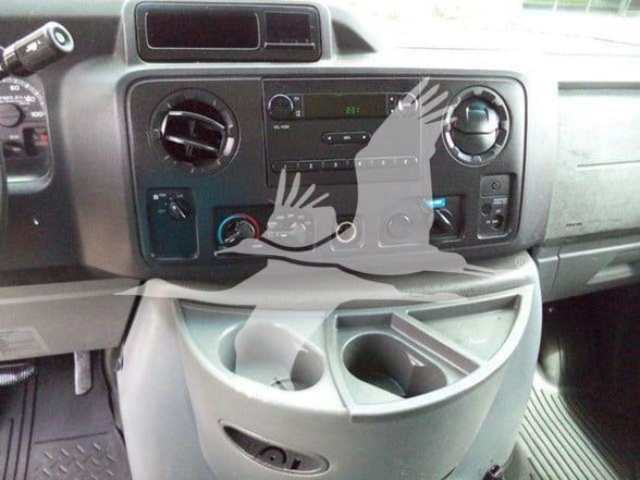 Dashboard of a 2011 Ford E450 front and center console with circular vents, radio, climate controls, and cup holder area visible.