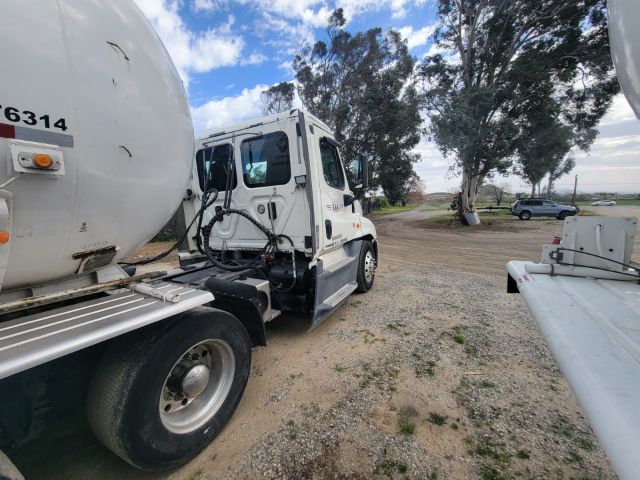 Truck with large cylindrical tanker attached, Freightliner Cascadia cab visible, front wheel, fuel lines, and trailer hitch; numbers 6314 and other marks on tank.