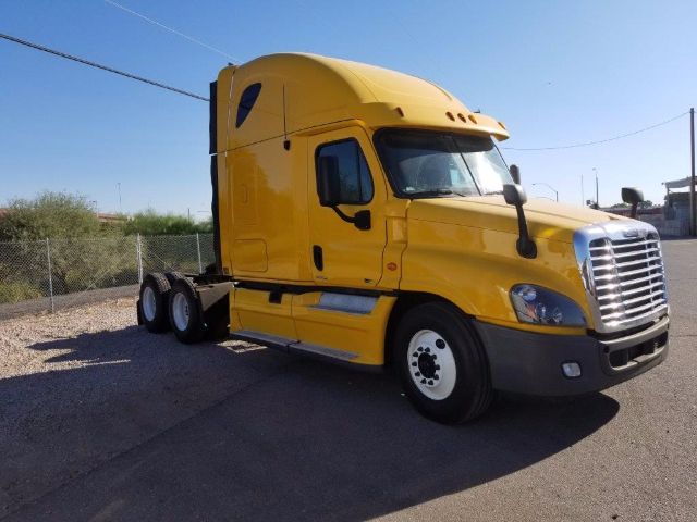 2012 Freightliner Cascadia conventional sleeper truck in yellow, side view showing cab and front grille, with clear sky.
