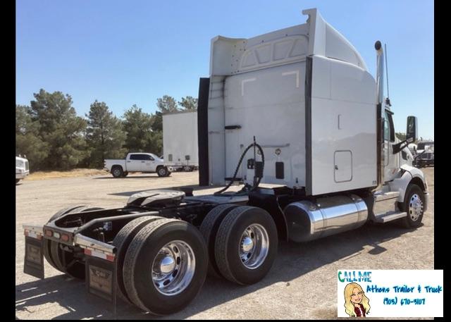 Peterbilt 579 conventional sleeper tractor rear view showing dual rear axles and fuel tanks.