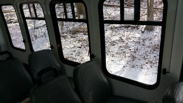 Interior of a 2009 Ford E-450 bus with multiple passenger seats and large windows showing a snowy outdoor scene.