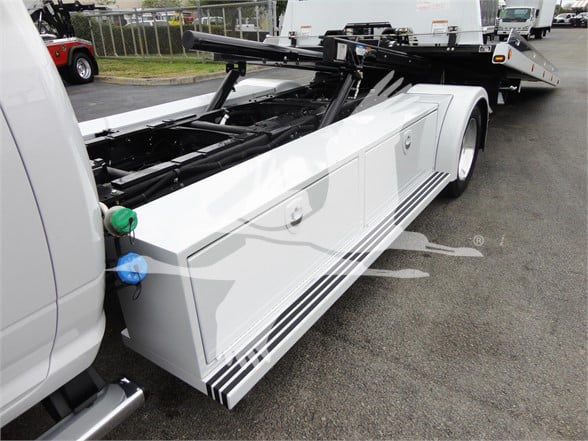 Ram 5500 tow truck side with equipment rack and storage compartments visible.