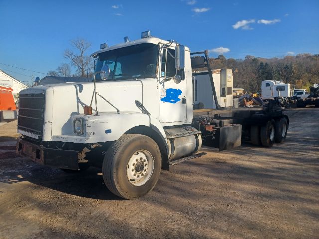 Volvo VG64 roll-off truck showing front cab and chassis with exposed fuel tank and wheel, doors, and side mirrors.