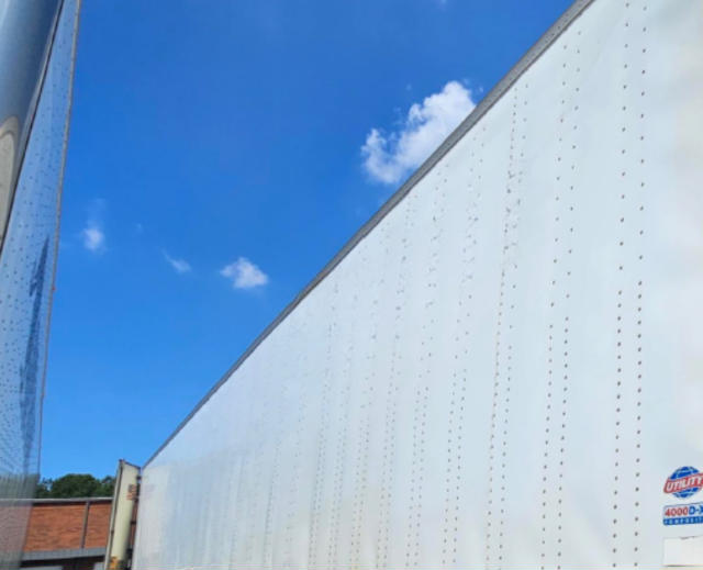 Trailer side with white composite wall and blue sky, small Utility 4000 D-X logo sticker visible.