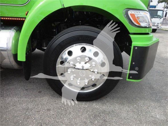 Peterbilt 337 front wheel area showing green cab and chrome wheel with tire, front fender and bumper.