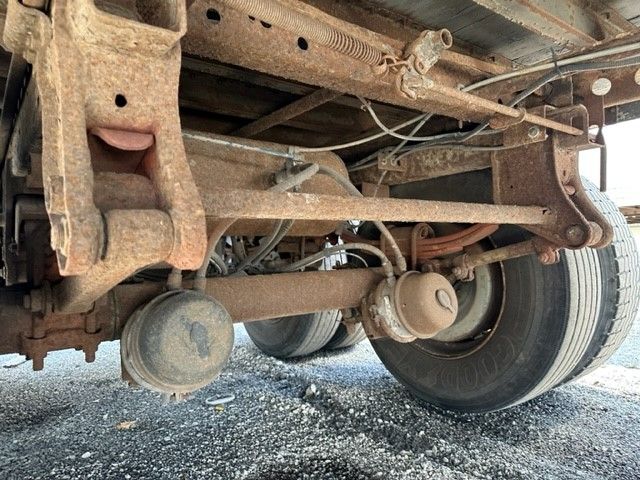 Undertruck view showing axle, leaf springs, and suspension components on a Wabash trailer. Rust present on frame rails and springs; rear dual wheel shown with tire.