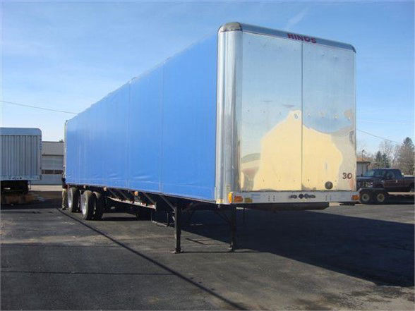 Fontaine Aero Conestoga tarp system trailer with blue curtain sides and silver front corner posts, viewed from rear-left on a paved lot.