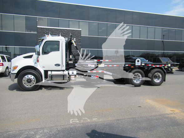 Kenworth T480 refuse truck in a dealership lot, chassis visible with side view, white cab, heavy-duty rear body
