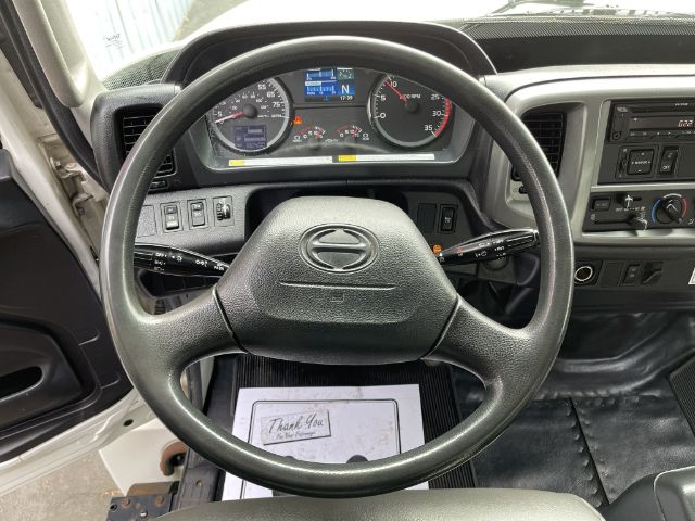 Steering wheel and dashboard of a 2017 Hino 268 box truck interior showing instrument cluster, digital display, and steering column controls.