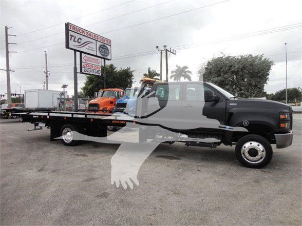 Truck with flatbed tow body in a dealership lot, 2023 International CV, stock number J98978, tow category, new condition.