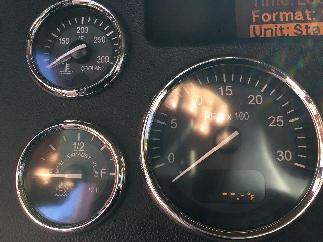 Peterbilt dashboard gauges showing coolant temperature, DEF/exhaust, and tachometer with rpm x100 scale; small digital readout bottom shows unit status.