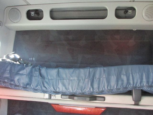 Volvo truck cab interior showing sleeper area with a blue padded cover over a storage area and a rear window; overhead console with vents and two circular lights.