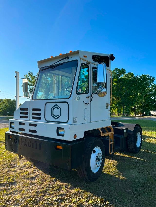 White yard truck with cab-forward design, capacity logo on the grille, black bumper with faint lettering, side mirrors, and a single rear axle setup.