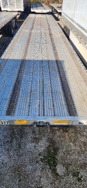 Trailer deck with metal planks and yellow reflectors on edge; worn surface with blue paint.