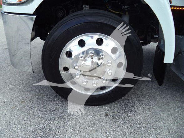 Wheel and front fender of a Peterbilt truck with chrome hubcap and lug nuts visible; no legible labels or serial numbers on the wheel.