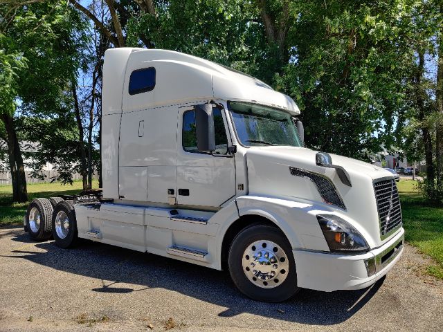 2017 Volvo 670 Conventional Sleeper truck side view showing white cab, black grille, dual rear axles, and chrome wheels.