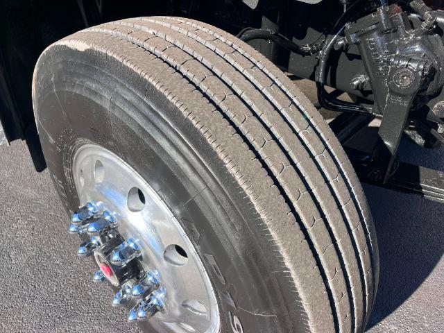 Truck wheel and dual rear tires of a Freightliner M2 106 showing aluminum wheel, lug nuts, and part of the suspension and brake assembly.