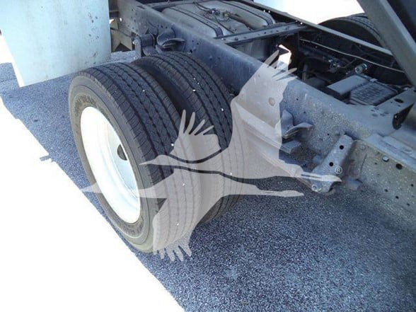 Isuzu NQR truck chassis showing dual rear wheels and frame undercarriage in a loading area.