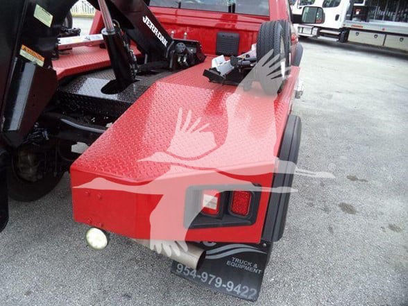 Ram 4500 tow truck rear quarter showing taillight area, red diamond plate bed, hitch area, and bumper with text.