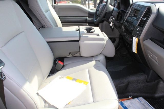 Interior of a 2022 Ford F-250 front seats and dashboard showing light gray cloth seating and center console.