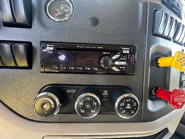 Peterbilt truck dashboard with aftermarket stereo unit, climate controls, and ignition switch; visible gauges and knobs.