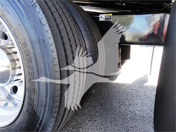Truck wheel and dual rear tires with metal frame; partial reflection shows a label sticker. Visible text on tire reads '255/75R22.5'