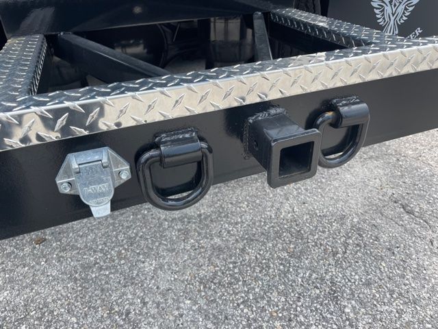 Freightliner Cascadia truck bumper showing hitch receiver and two loop tie-down points with diamond plate step above.