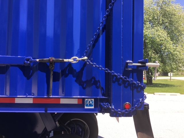 Blue 40 ft square dump trailer hitch chains visible rear view with reflective striping and rear latch