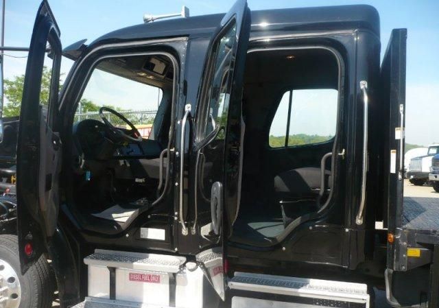 Freightliner M2 cab doors open showing interior steering wheel and seats in the cab.