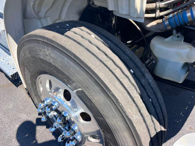 Front left wheel and dual-tire assembly of a heavy-duty Freightliner truck showing chrome lug nuts and tread pattern.