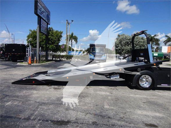 Tow truck flatbed with low-profile wheel and ramp, International MV visible in image