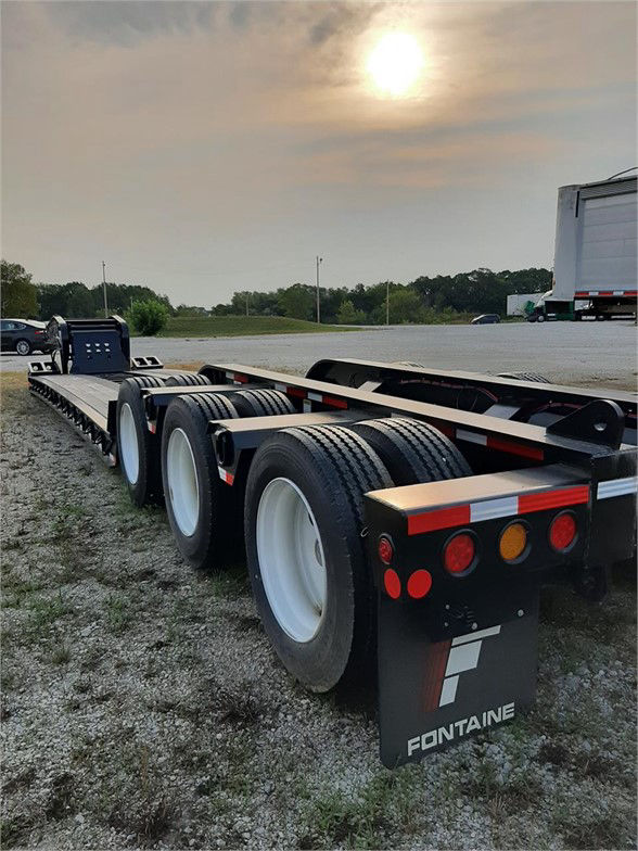 Fontaine 55 ton steel lowboy trailer with 26ft deck, viewed from rear-left side showing tandem axles and black paint with red/white reflective stripes.