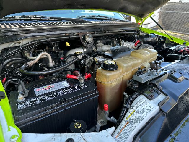 Ford F-550 engine bay with battery, coolant reservoir, and power steering components visible.