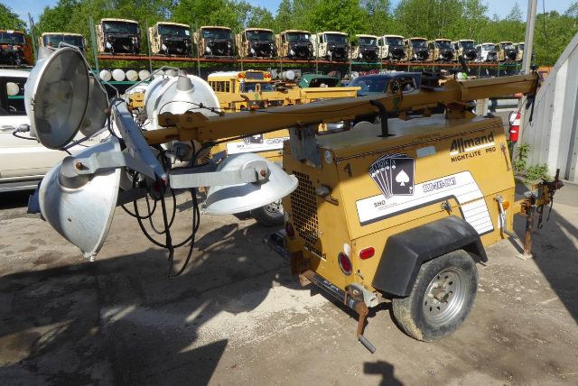 Allmand Night Lite Pro portable light tower mounted on a yellow trailer with detachable mast andight lamps in front, utility equipment, multiple units in background.