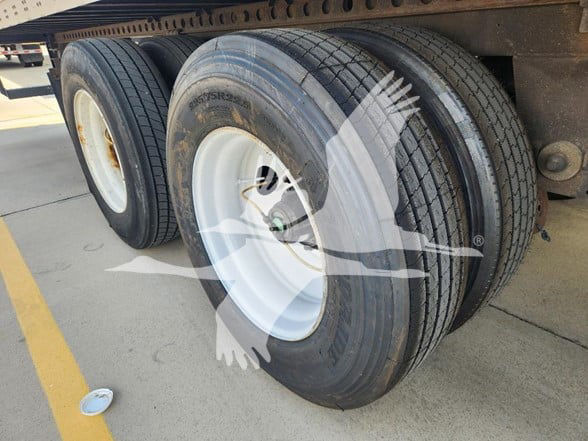 Wabash trailer wheels and tires showing dual rear axle with white rims and black tires.
