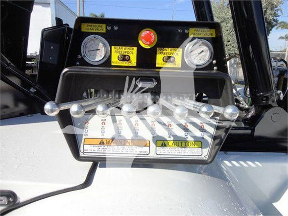 Control panel with gauges and levers on Freightliner M2 106, warning and caution labels visible, front valves labeled, multiple switches and knobs.