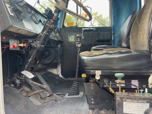Peterbilt 359 cab interior showing steering wheel, gear selector, seat, and dash with controls; transmission tunnel and floor pedals visible.