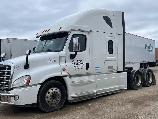 Truck cabin of a white 2017 Freightliner Cascadia with ASMK Transfer decals, long trailer, front left view, VIN and truck numbers visible.