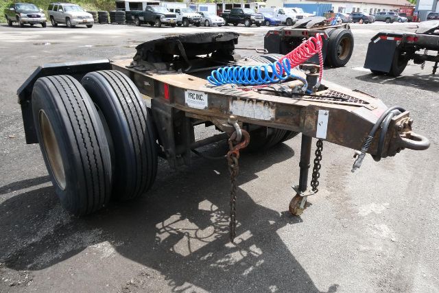 Fruehauf ELFI dolly trailer chassis with tandem rear axles and coiled air lines; VIN plate and stock tag visible.