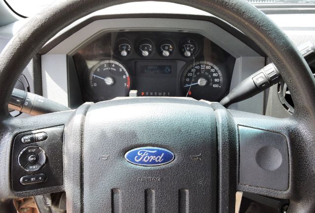 Ford steering wheel with instrument cluster behind; visible text includes Ford logo on airbag cover and various gauges, with transmission indicator on dash.